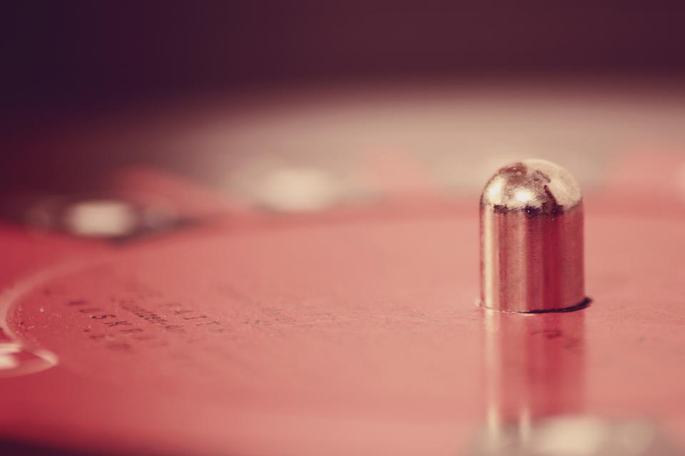Close-up of a record player spindle on a red turntable