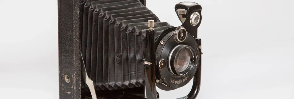 An antique folding bellows camera on a white surface
