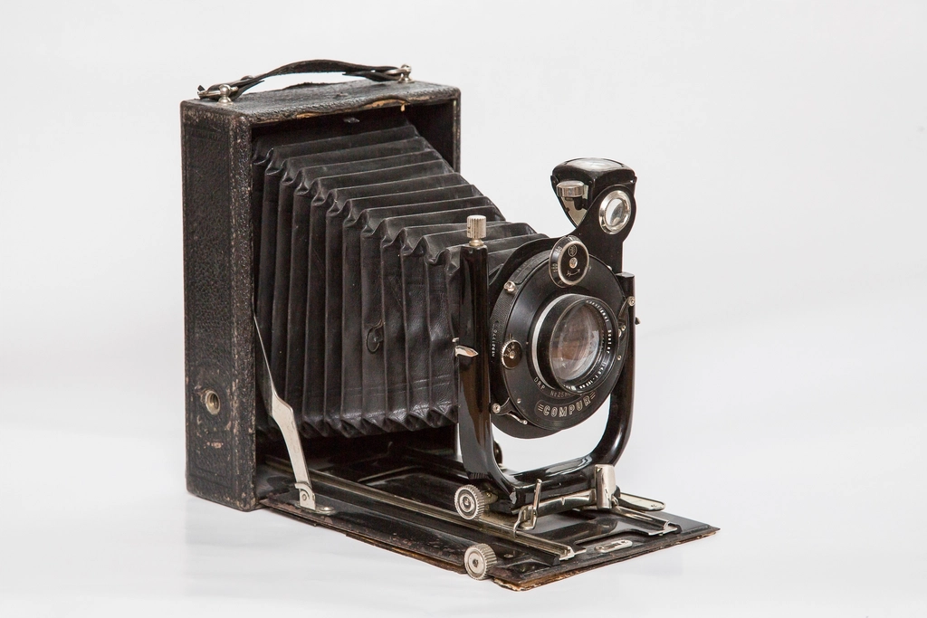 An antique folding bellows camera on a white surface